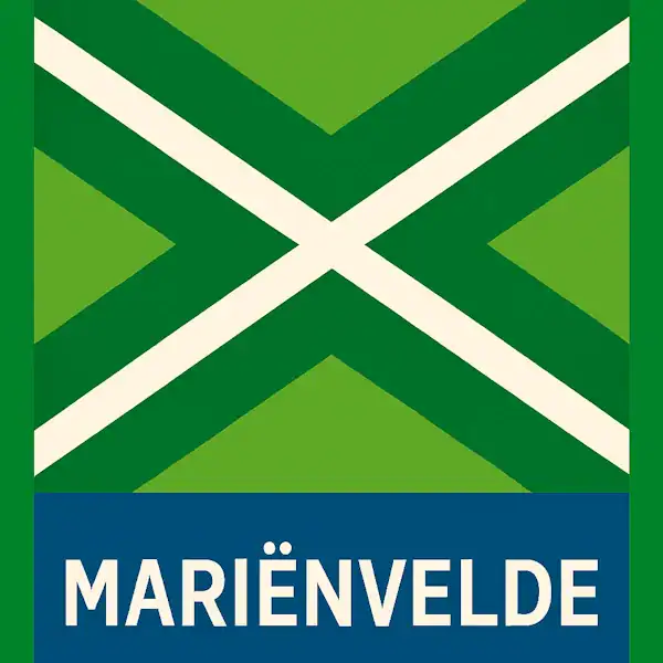 Plaatsnaambord met de tekst "MARIËNVELDE" in witte hoofdletters op een blauwe balk onderaan. Daarboven een groene vlag met een wit kruis, omlijst door een donkergroen kruispatroon, met rondom de vlag uitsluitend groene achtergrond.